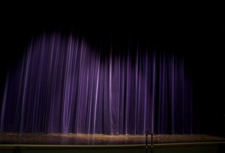 Dark theater stage and curtains evoking the dreamlike puppet imagery of Thomas Ligotti's horror fiction